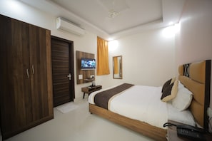Una habitación de hotel con una cama de madera, un televisor, un espejo y un armario.