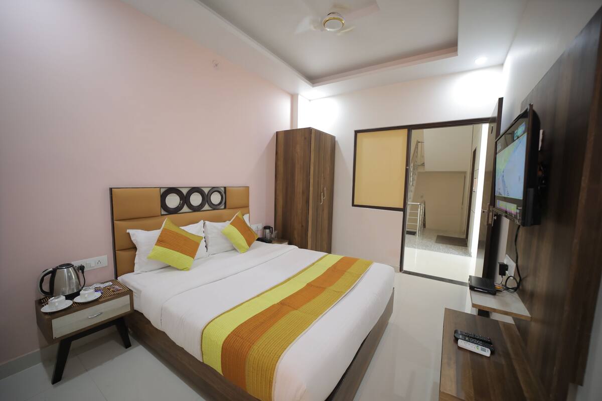 A hotel room with a bed, a nightstand, a TV, and a wardrobe.