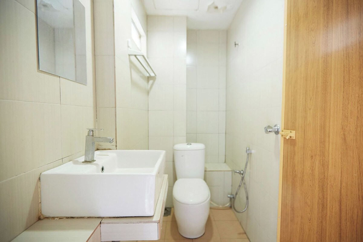 Un baño pequeño y limpio con lavamanos, inodoro y ducha blancos.