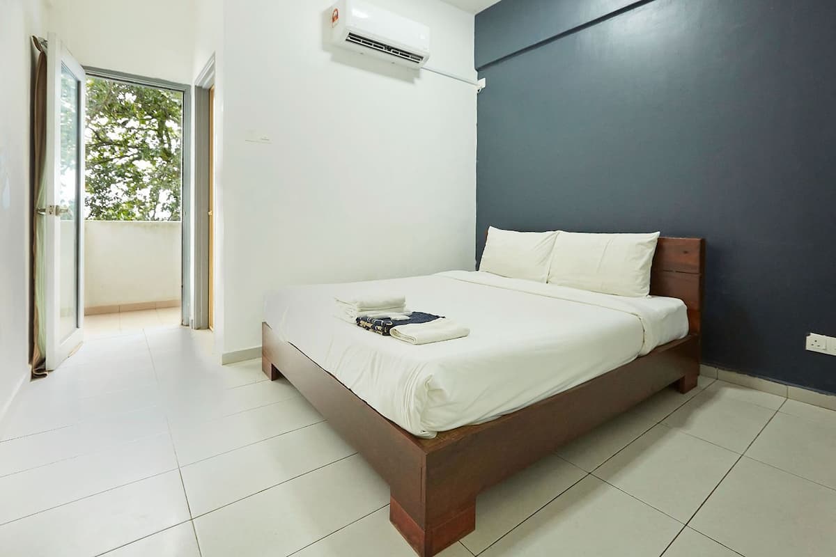 A neatly made bed with white linens, a wooden headboard, and a white air conditioning unit mounted on the wall.