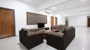 A spacious lobby with a modern sofa set, a flat-screen TV, and a patterned wall decoration. - Mawar Villa (Kuantan)
