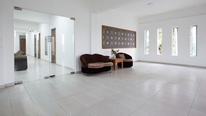 A spacious room with a large mirror, two sofas, a small table, and a decorative wall panel. - Mawar Villa (Kuantan)