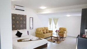 A hotel room with a bed, two sofas, a coffee table, and an air conditioning unit. - Mawar Villa (Kuantan)