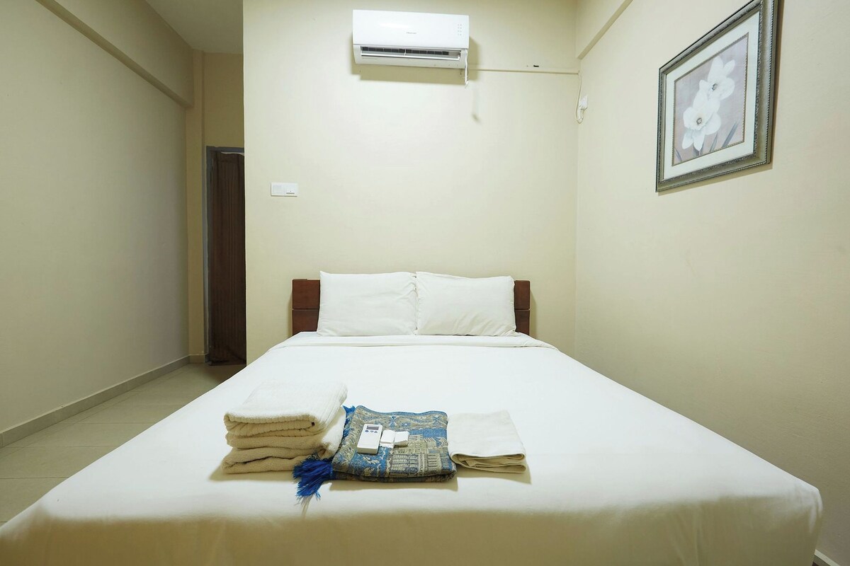 Una cama bien hecha con sábanas blancas, un edredón doblado y una almohada decorativa.