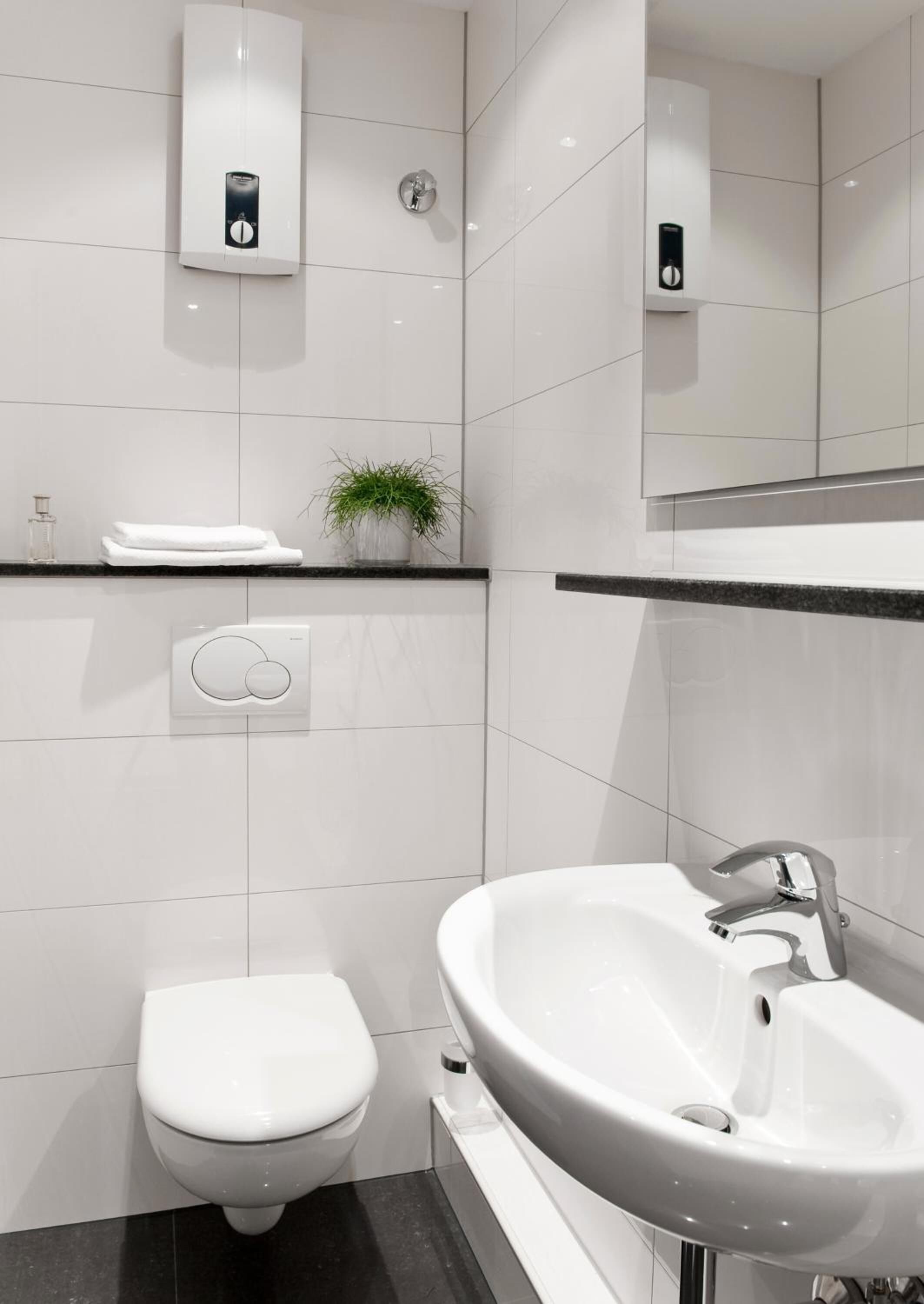 Un bagno moderno con un water, un lavandino e un dispenser di sapone a parete.