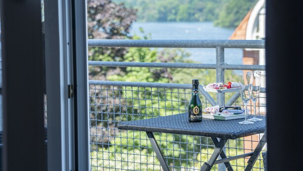 A balcony with a table set for a small gathering, featuring a bottle and glasses. - Apartment-Hotel Dieksee Eck (Malente)