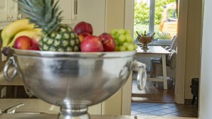 A kitchen with a fruit bowl on the counter, a dining table, and a view of the outside. - Apartment-Hotel Dieksee Eck (Malente)