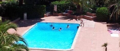 Une piscine entourée de palmiers et un bâtiment jaune.