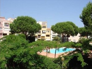 Área residencial com edifícios de apartamentos, piscina e vegetação exuberante.