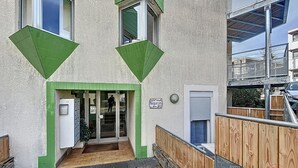 A building with a green triangular design, a door with a mailbox, and a wooden fence.