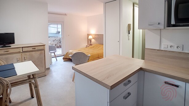 A compact hotel room with a bed, a desk with a chair, a television, and a balcony with a view.