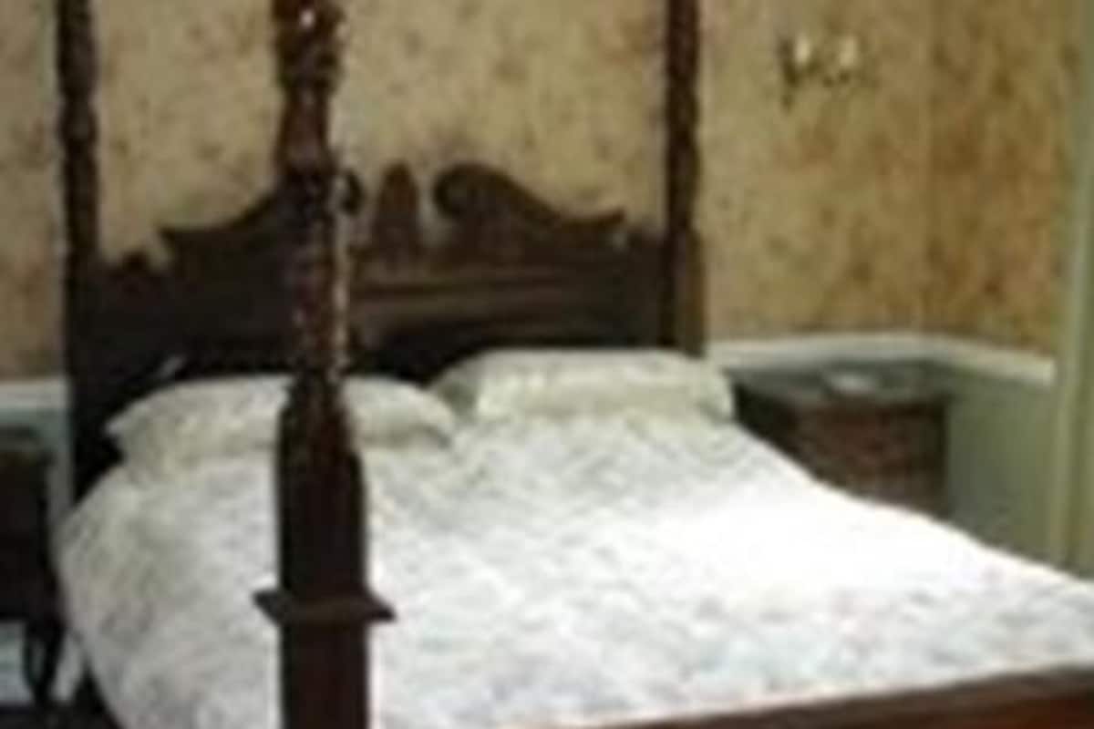 A four-poster bed with a wooden frame and a white bedspread.