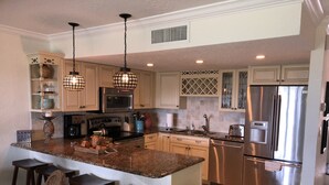 A modern kitchen with granite countertops, stainless steel appliances, and pendant lighting. - THE BEACH SHACK, a stylish oceanfront townhouse on quiet corner of Indialantic! (Indialantic)