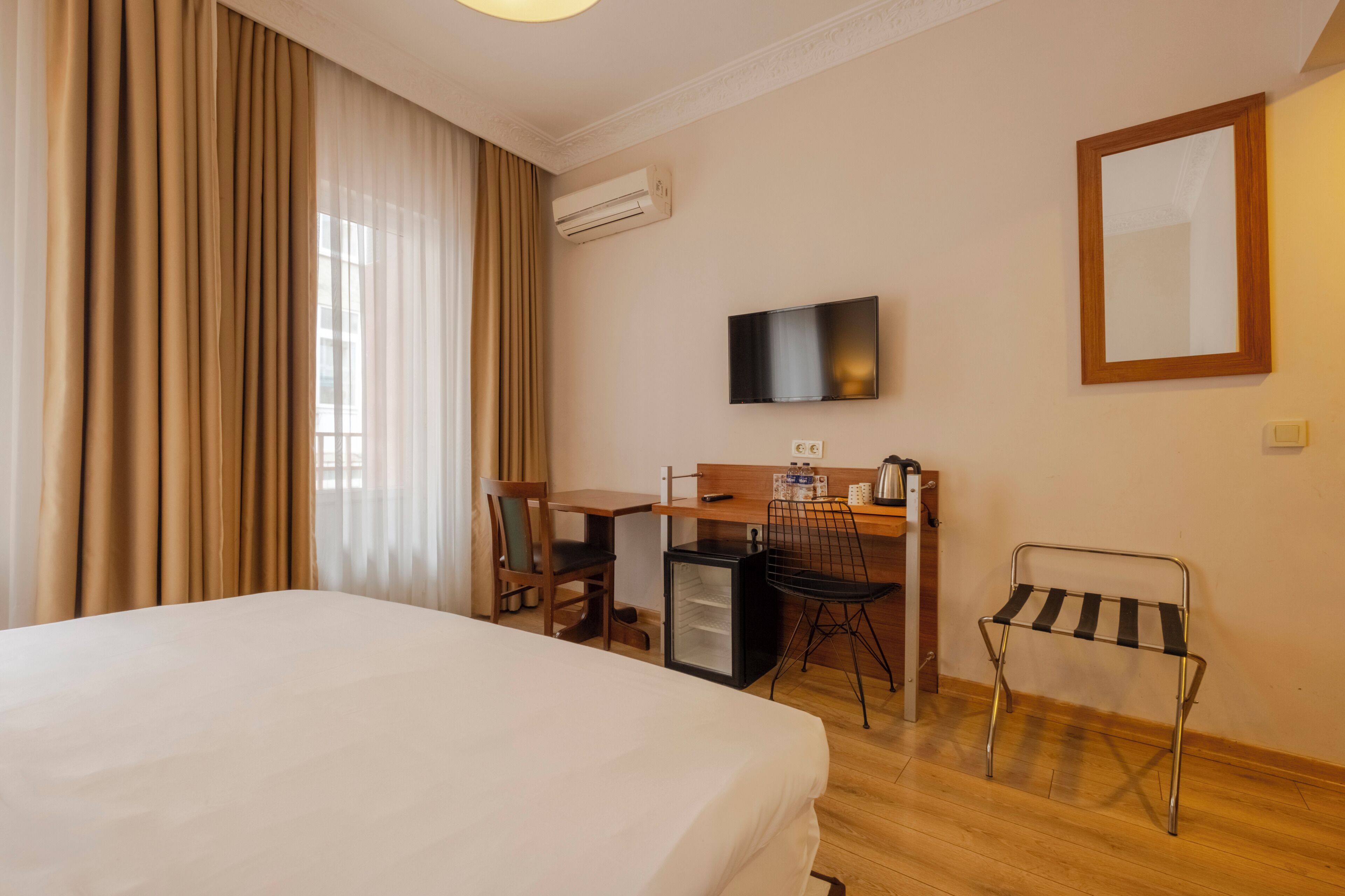 Ein Hotelzimmer mit Bett, Schreibtisch, Sessel, Fernseher und Spiegel.