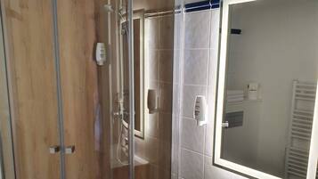 A modern bathroom with a glass-enclosed shower, a white sink, and a large mirror.