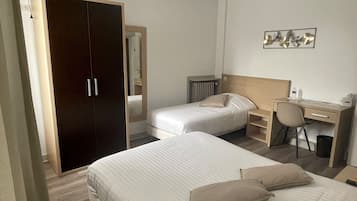A hotel room with two beds, a wardrobe, a desk, and a chair.