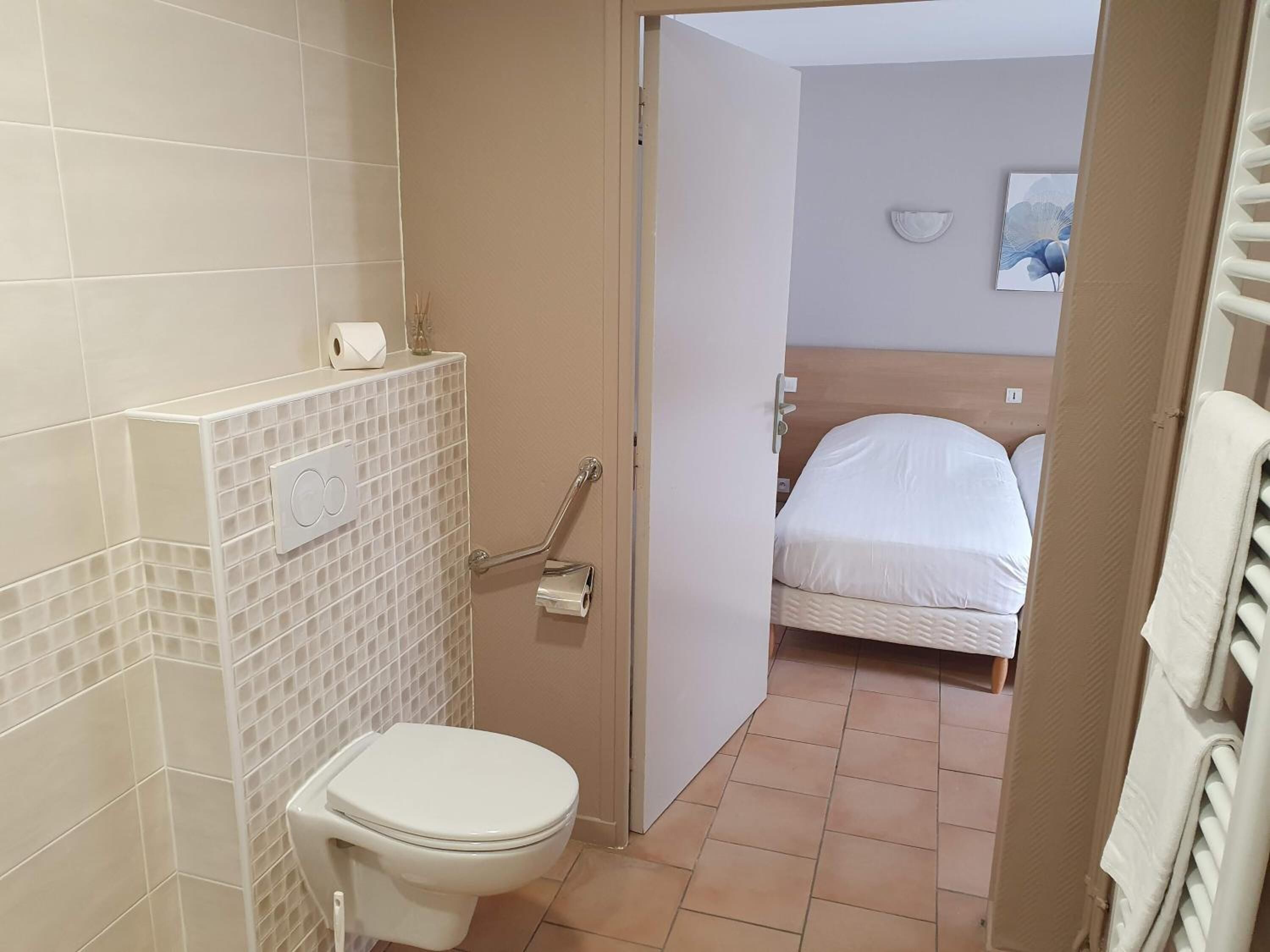 Ein Badezimmer mit Toilette, Haltegriff und Duschbereich.
