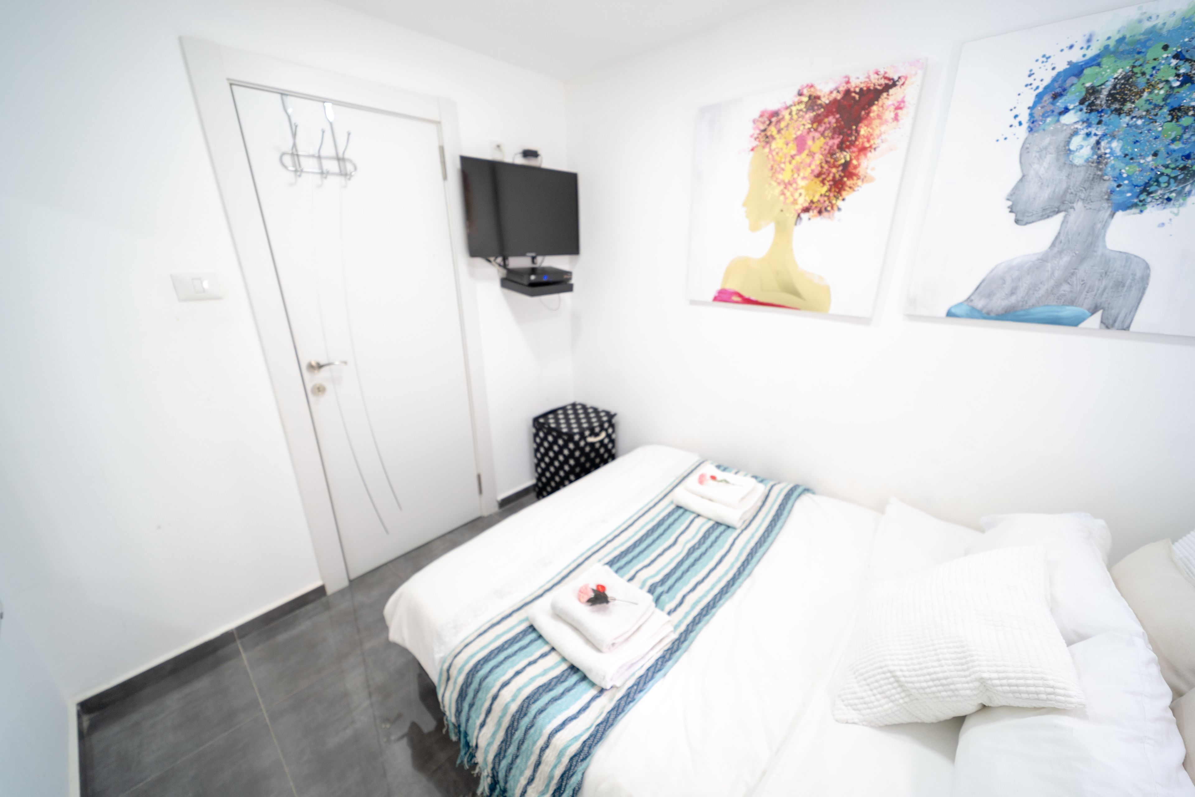 Une chambre d’hôtel avec un lit, un téléviseur fixé au mur et des œuvres d’art accrochées au mur.