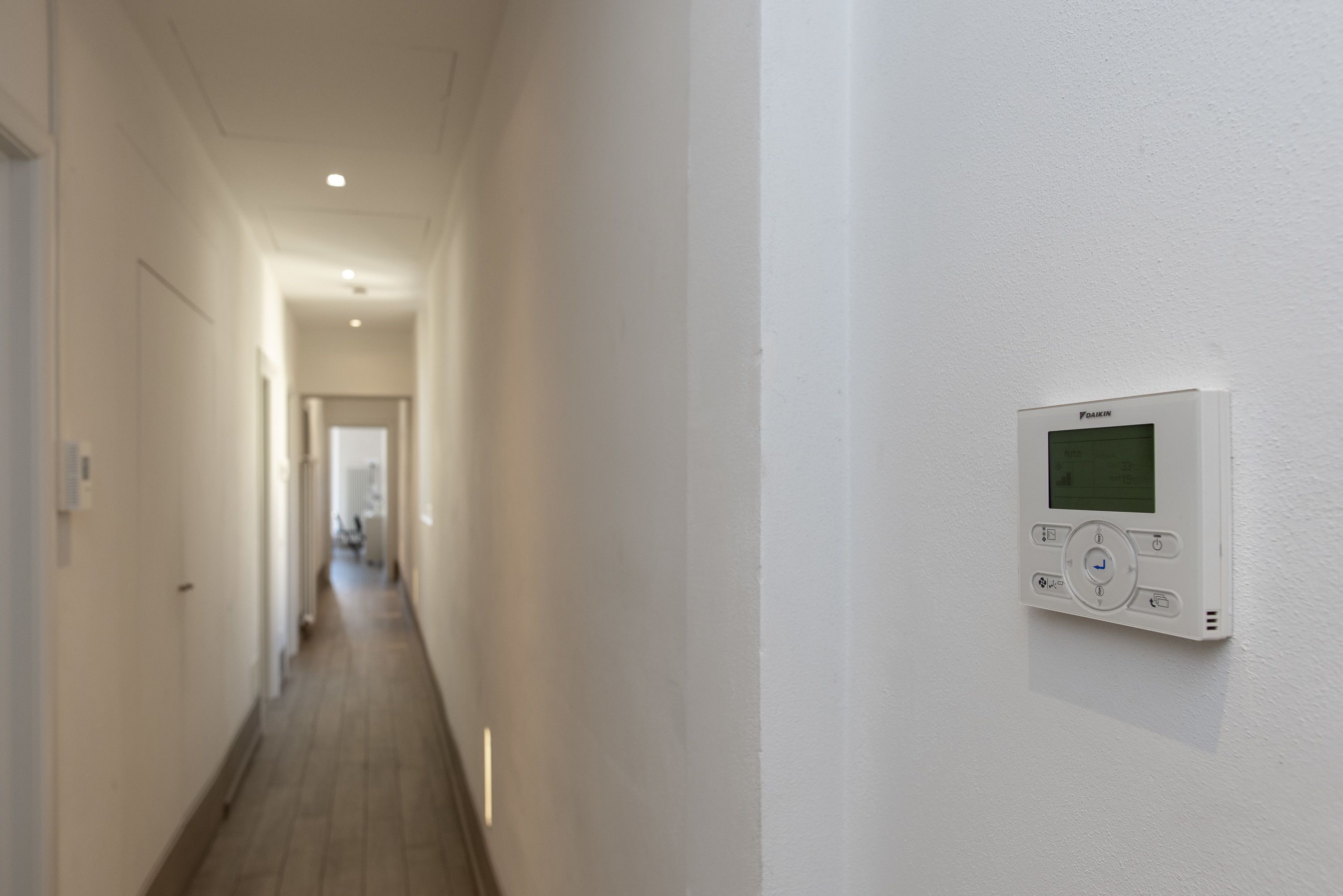 A hallway with a thermostat on the wall.