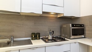 Cozinha moderna com armários brancos, fogão de aço inoxidável e micro-ondas.