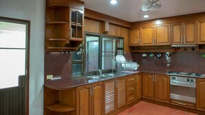 A kitchen with wooden cabinets, a stainless steel sink, and a built-in oven. - Xanadu Pool Villa at Phala (Ban Chang)