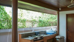 A covered outdoor kitchen area with a sink, stove, and cabinets. - Xanadu Pool Villa at Phala (Ban Chang)
