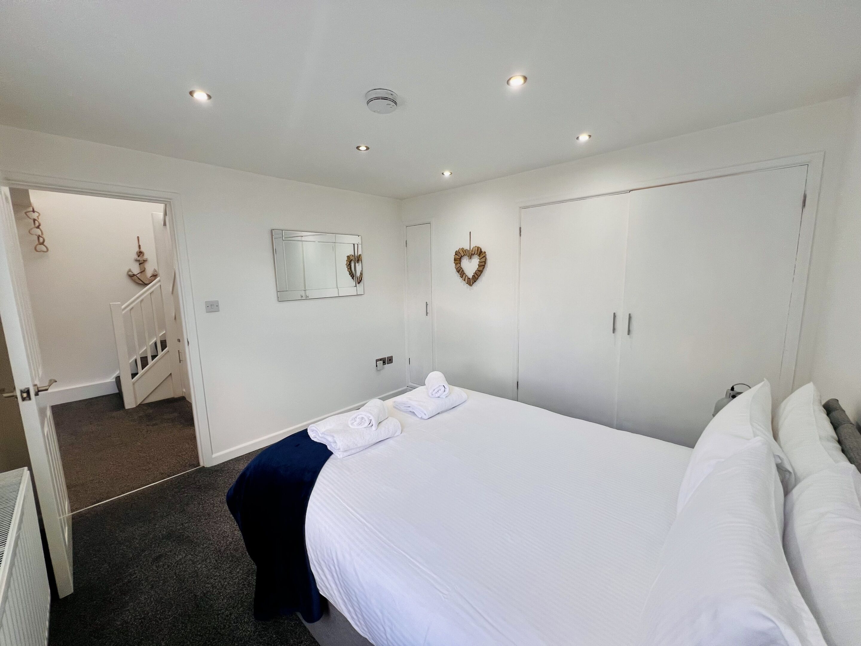 A hotel room with a bed, a wardrobe, a mirror, and a staircase leading to another room.
