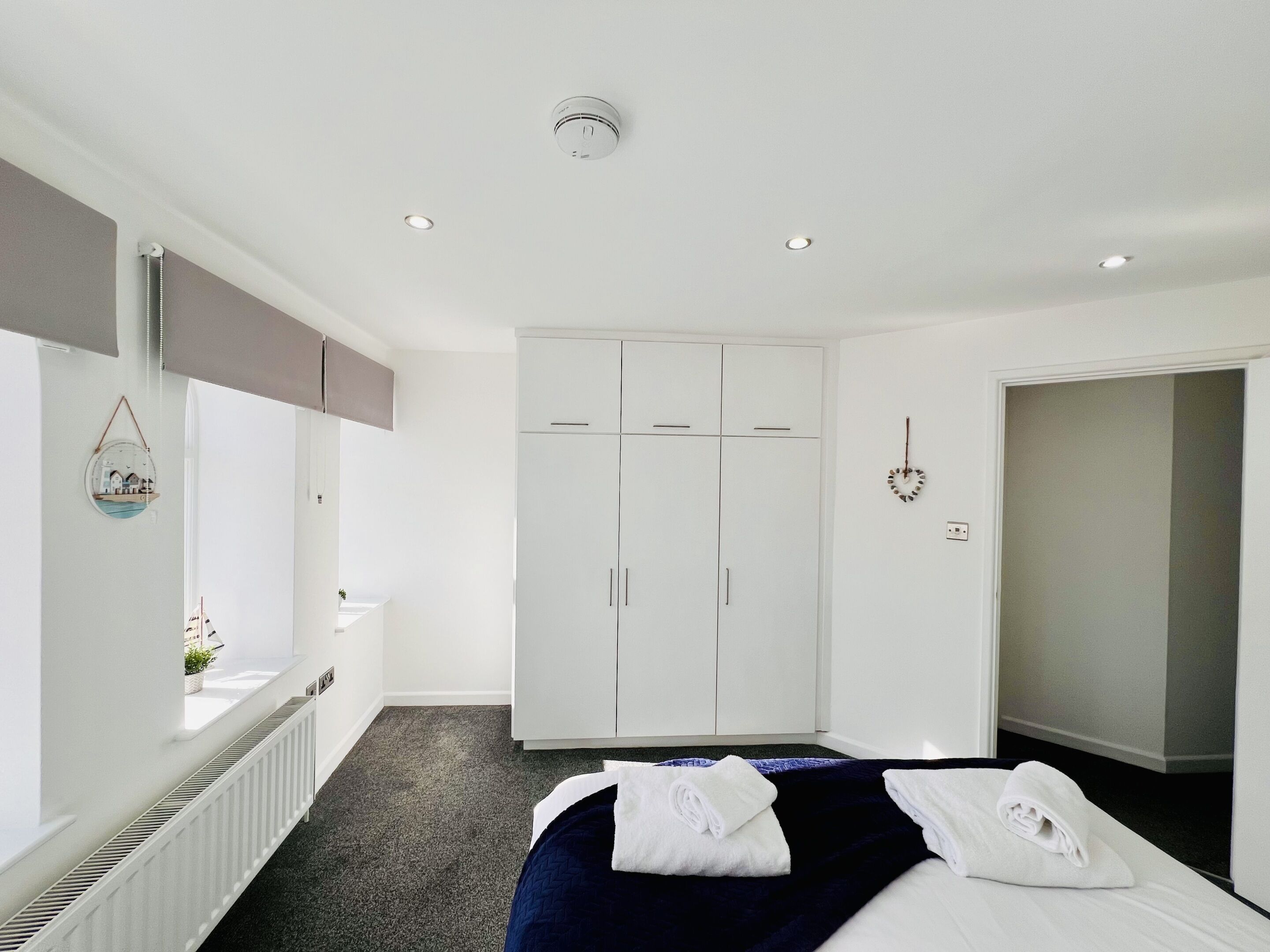 A hotel room with a bed, a wardrobe, a radiator, and a window with a view of the outside.