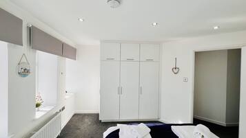 A hotel room with a bed, a wardrobe, a radiator, and a window with a view of the outside.