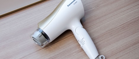 Ein Panasonic Haartrockner mit weißem Gehäuse und transparenter Düse auf einer Holzoberfläche.