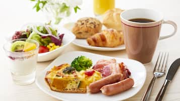 Una escena de desayuno con un plato de comida, un vaso de jugo, un croissant y una taza de café.