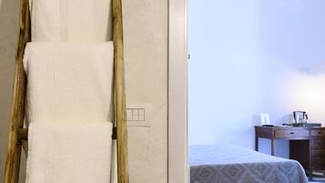 Une échelle en bois, avec des serviettes blanches appuyées contre un mur, mène à une pièce où se trouvent un lit et un bureau.