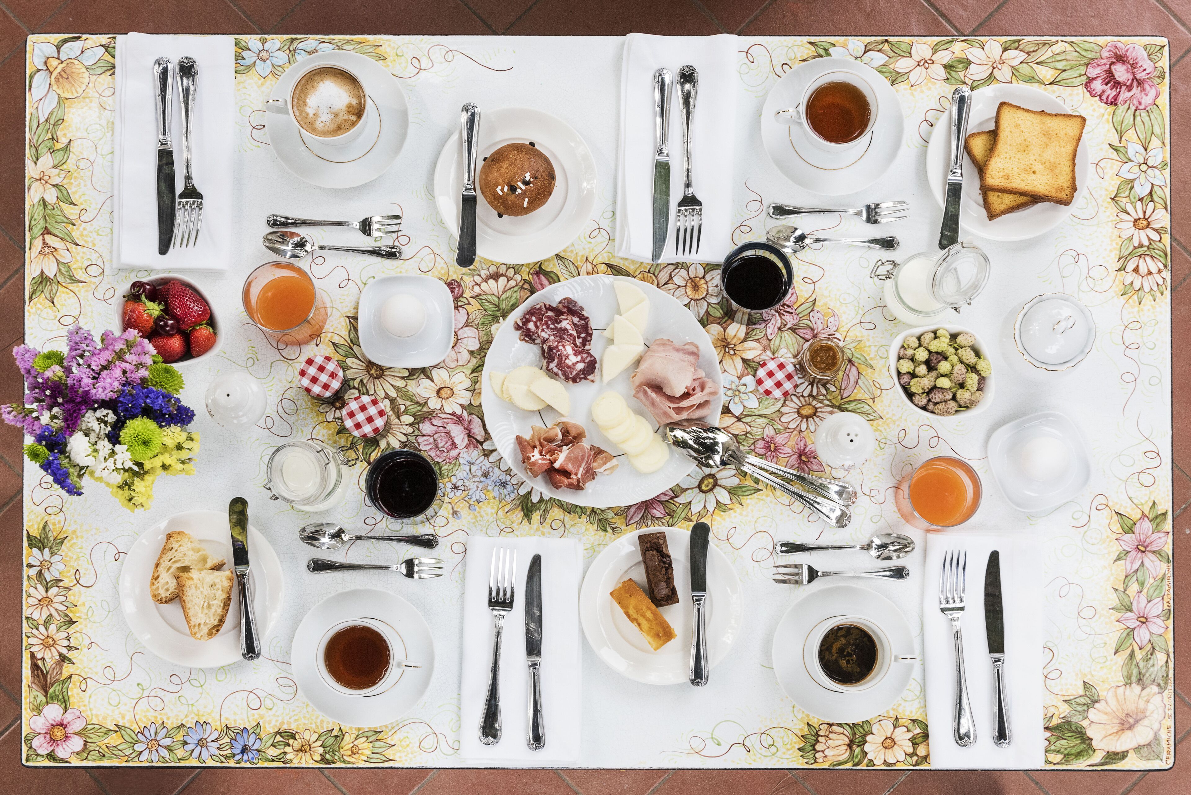 Een ontbijttafel gedekt met borden eten, bekers en bestek.