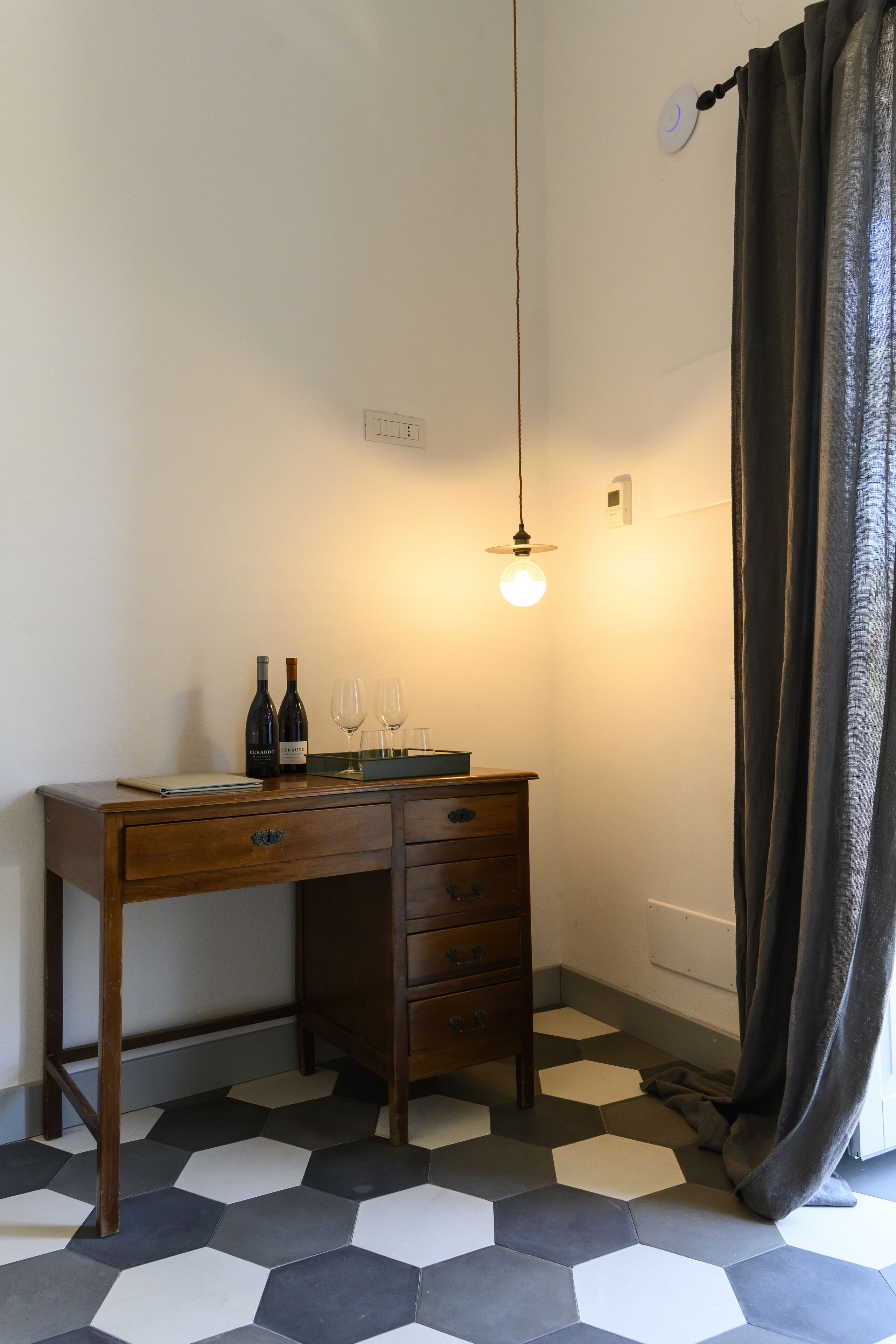 A room with a wooden desk, two wine bottles, and two wine glasses.