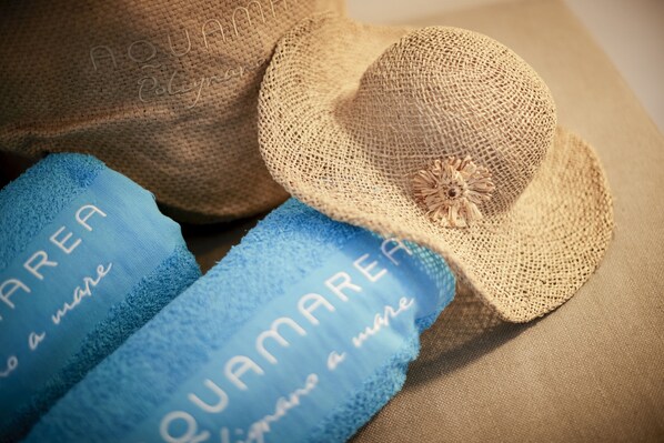 Deux chapeaux de paille et deux serviettes bleues, toutes les deux ornées de l’inscription « QUAMAREA » et « AQUAMAREA ».