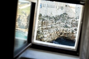 En stenvæg med en smal passage og et vindue med udsigt over et klippefyldt landskab.
