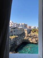 Uma cidade costeira com uma ponte de pedra histórica e águas azul-claras.