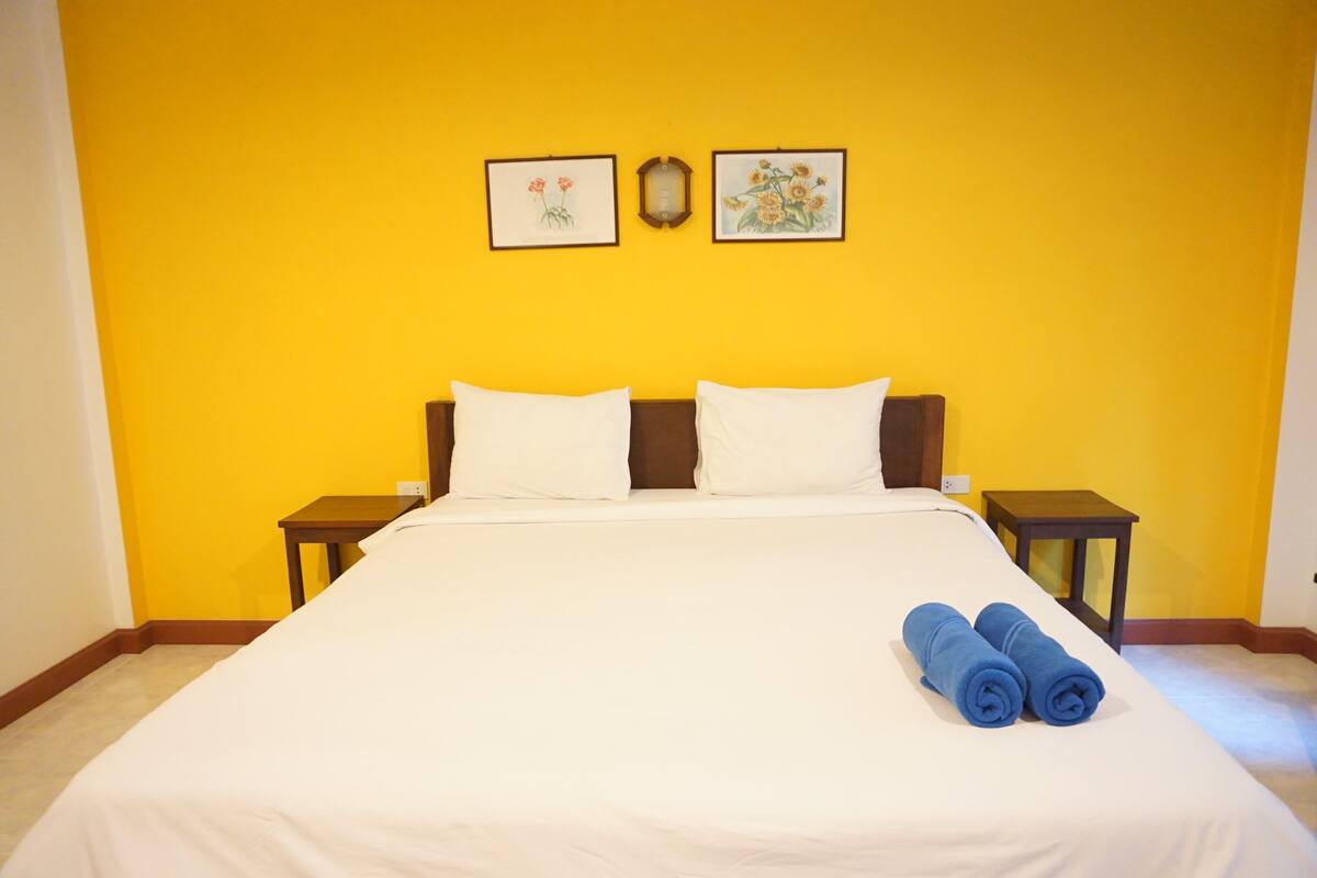 A hotel room with a large bed, two nightstands, and two framed floral pictures on the wall.