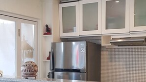A modern kitchen with a central island, white cabinetry, and a stainless steel refrigerator. - Villa Fei (Jimbaran)
