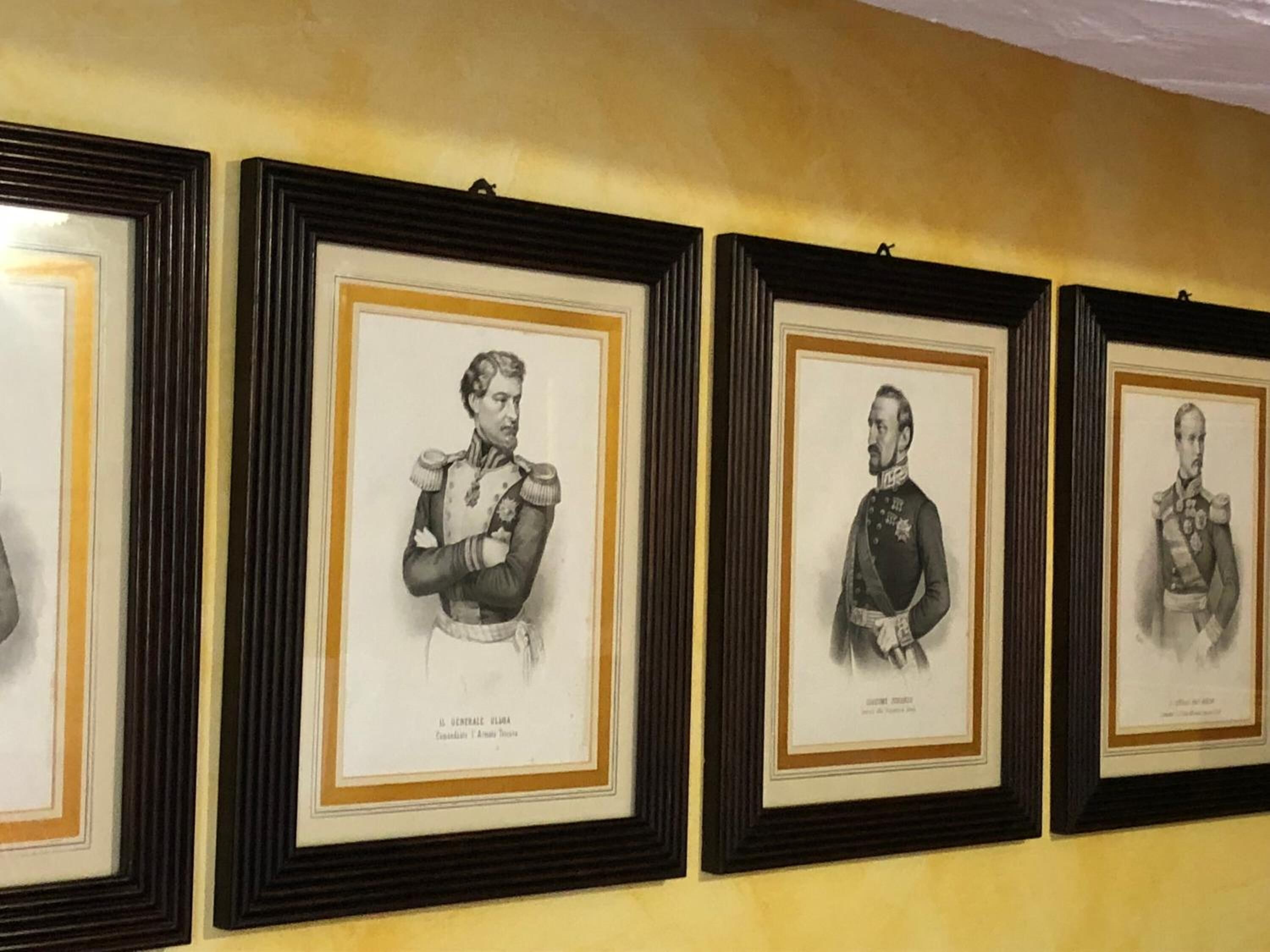 Eine Reihe von gerahmten Porträts an einer Wand.