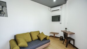 Una sala de estar moderna con un sofá, un televisor montado en la pared, una pequeña mesa de madera y una silla.