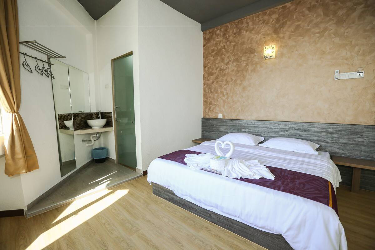 A hotel room with a bed, a bathroom, and a mirror.