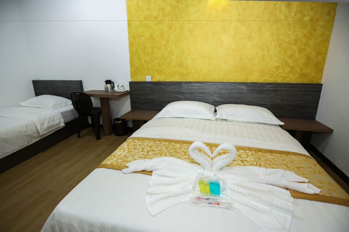 A hotel room with two beds, a desk, and a headboard with a yellow accent wall.