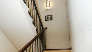Una escalera de madera con barandas negras y un aplique en la pared.
