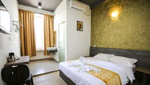 Habitación de hotel con cama, escritorio, silla, lavamanos y ventana con cortinas.