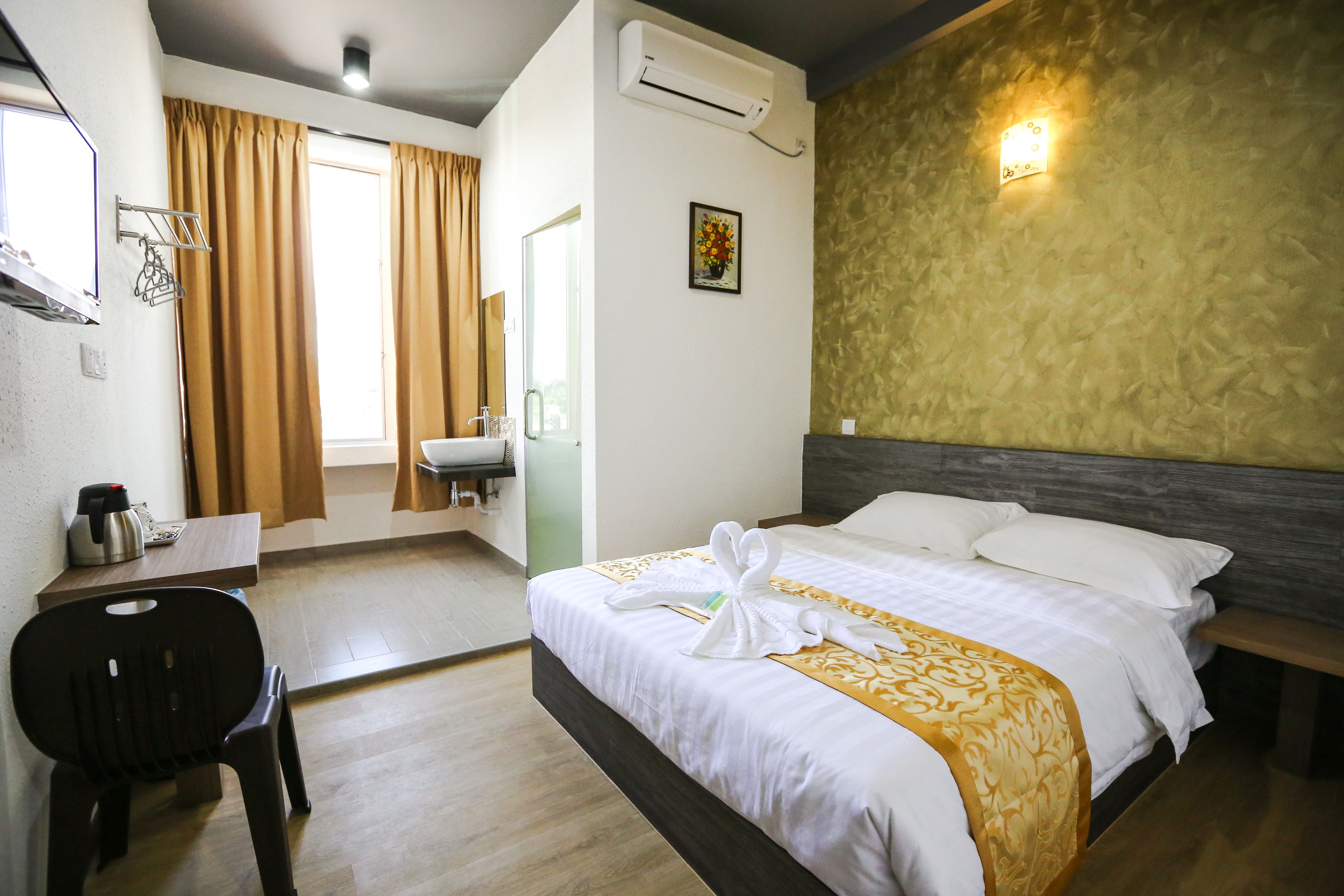 A hotel room with a bed, a desk, a chair, a sink, and a window with curtains.