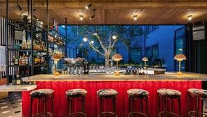Un bar doté d’un comptoir rouge rembourré, de plusieurs tabourets et d’une variété de bouteilles et de verres.
