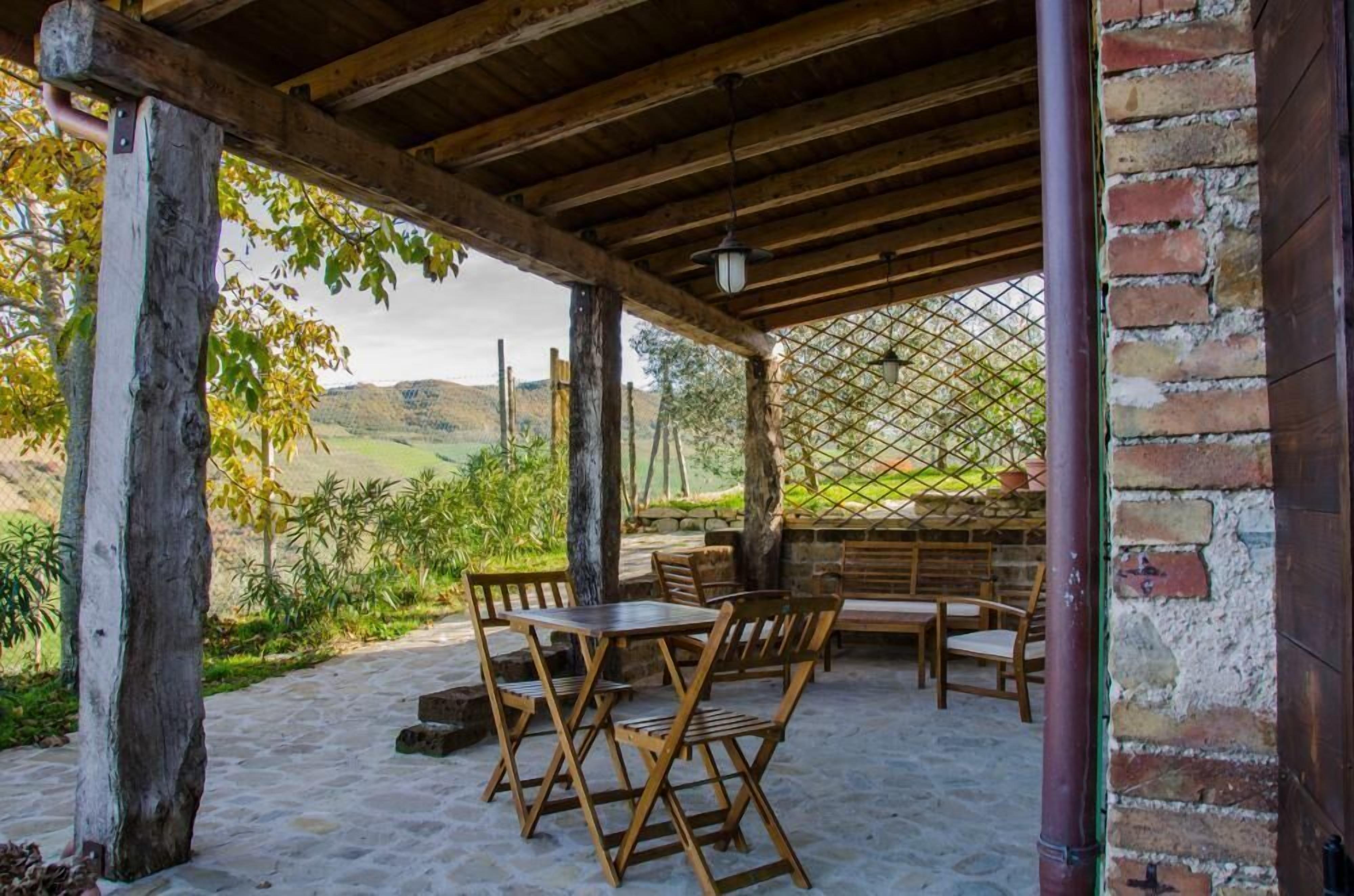 Une terrasse extérieure avec des meubles en bois, un mur en briques et une vue sur un paysage verdoyant.