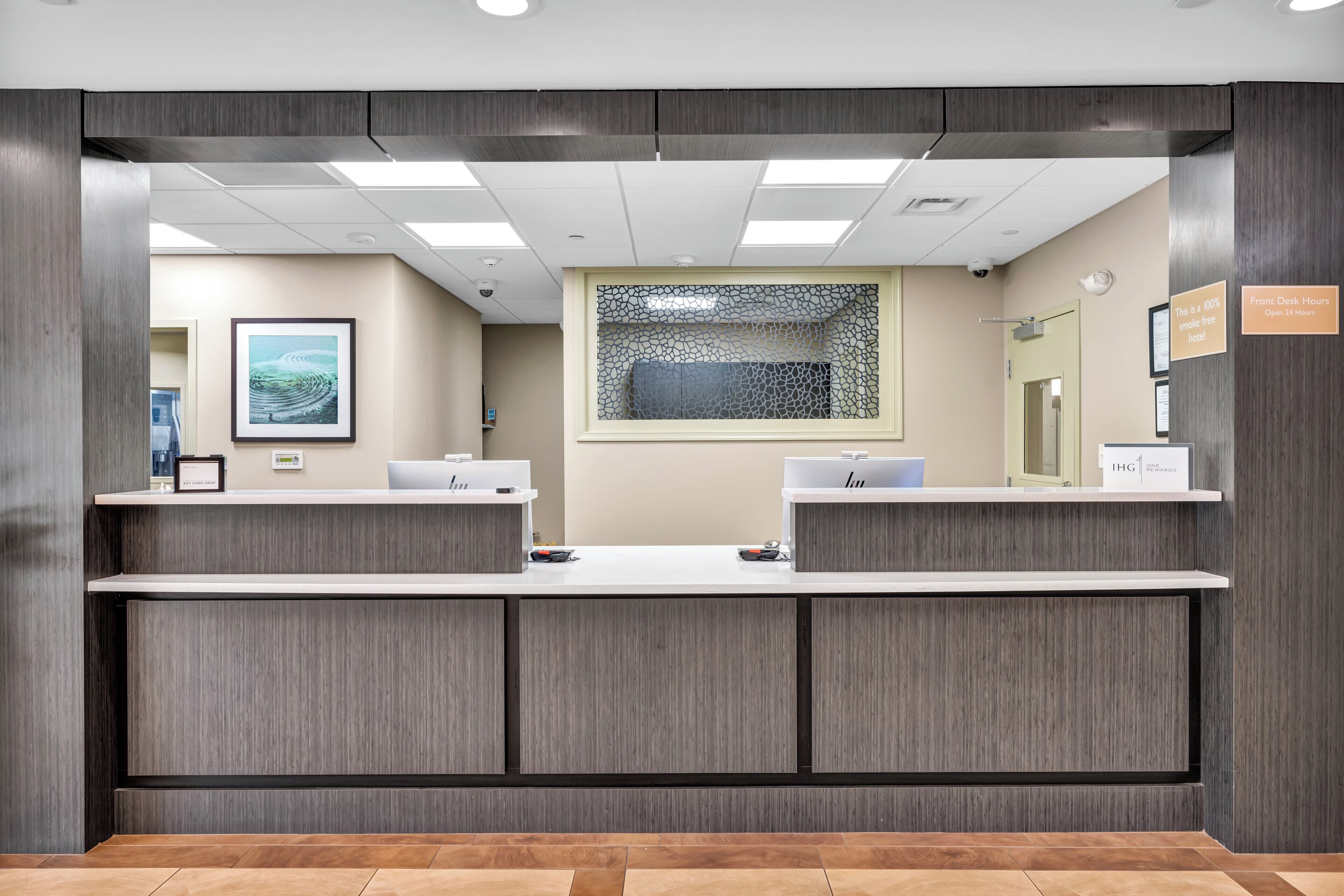 A reception desk with two counters, a framed artwork on the wall, and a sign indicating 24-hour service.