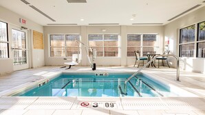 A pool area with a diving board, a chair, and a table with chairs. - Candlewood Suites Dumfries - Quantico by IHG (Dumfries)